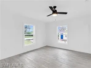 an empty room with windows and ceiling fan