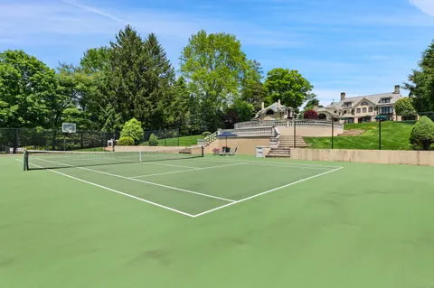 a view of a tennis ground with large trees