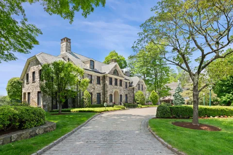 a view of a big house with a big yard plants and large trees