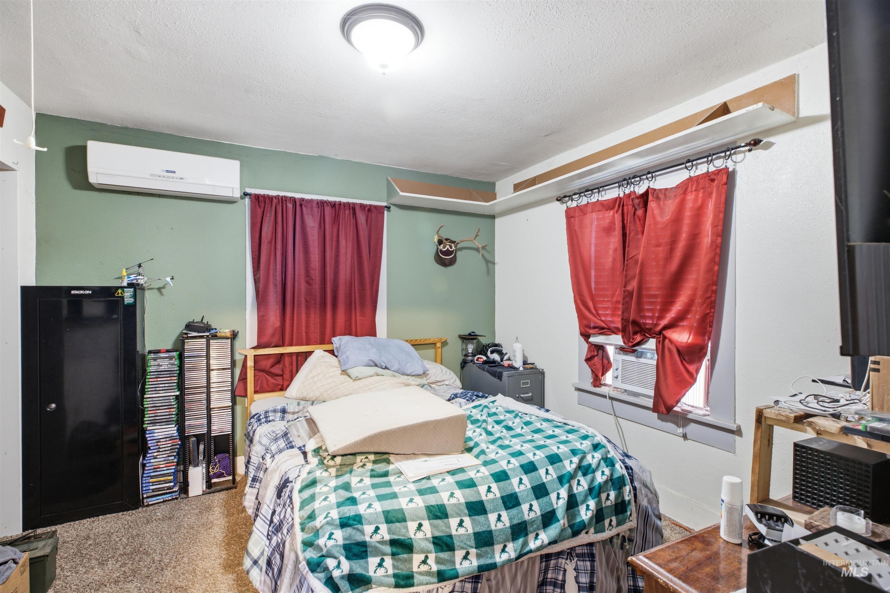 735 Oak Street Potlatch, ID 83855 - Photo 9 of 30 Carpeted bedroom featuring a ceiling-mounted light fixture, a wall-mounted mini-split AC unit, and a window with a built-in air conditioning unit