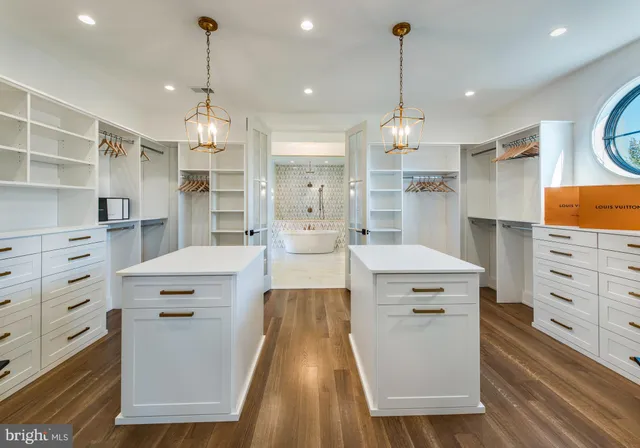 a large kitchen with kitchen island a stove a sink dishwasher a refrigerator and white cabinets with wooden floor