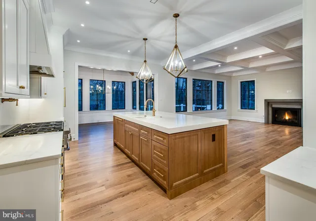 a large kitchen with stainless steel appliances a large counter top a stove and a wooden floors