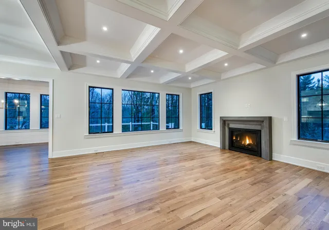 a view of an empty room with wooden floor fireplace and a window