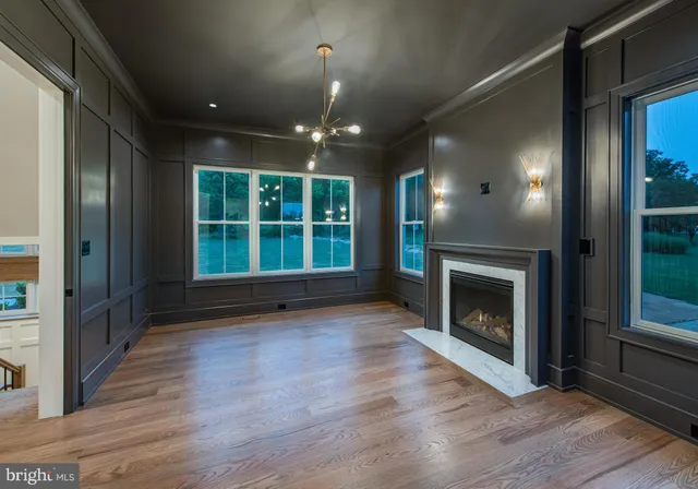 a view of an empty room with wooden floor fireplace and a window