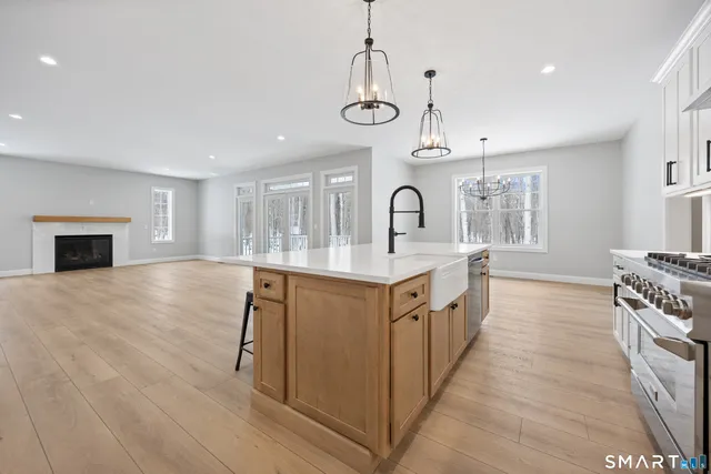 a kitchen with stainless steel appliances a white stove top oven a sink a chimney and a center island