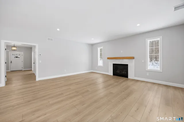 an empty room with wooden floor and fireplace