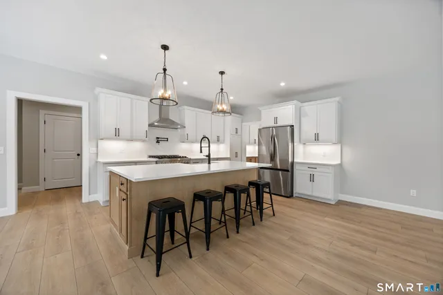 a kitchen with stainless steel appliances granite countertop a kitchen island hardwood floor and a sink