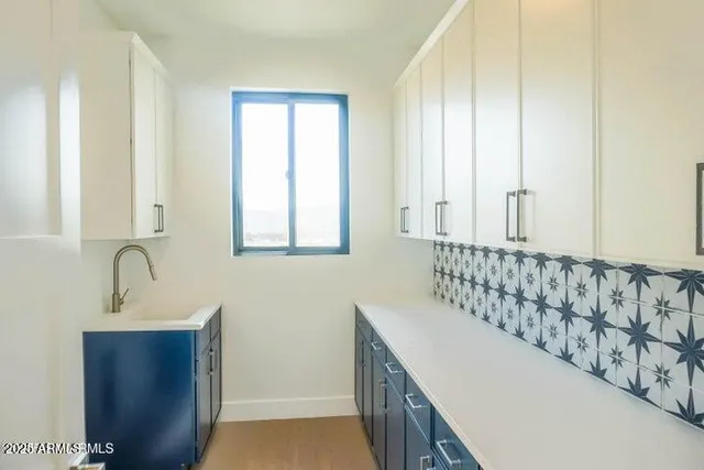 a kitchen with stainless steel appliances granite countertop a refrigerator a sink and white cabinets with wooden floor