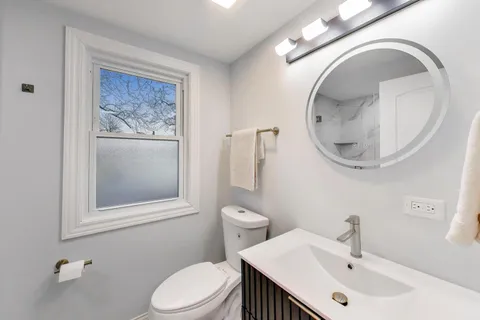 a bathroom with a toilet a sink and mirror