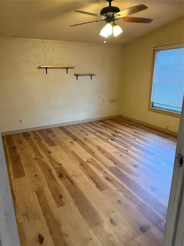 a view of a room with a ceiling fan and hardwood floor