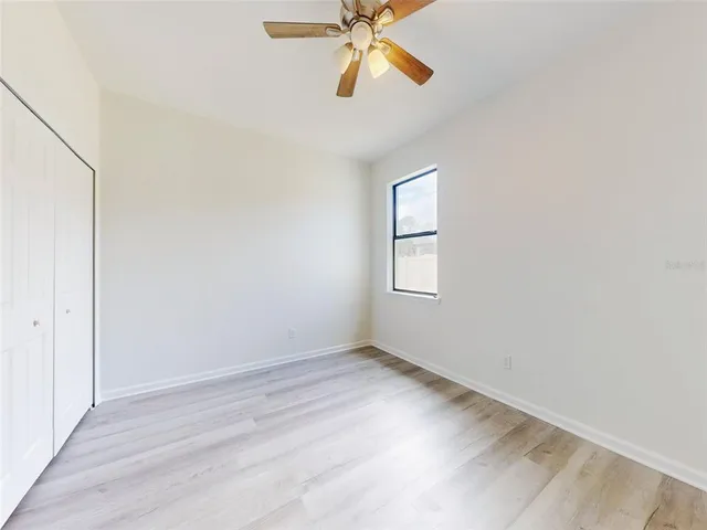 an empty room with windows and fan