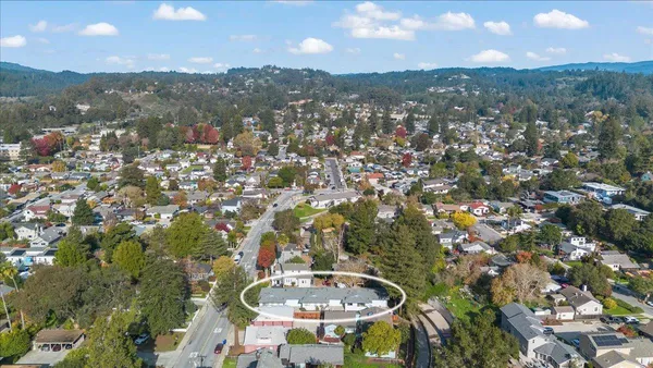 an aerial view of residential houses with outdoor space and trees