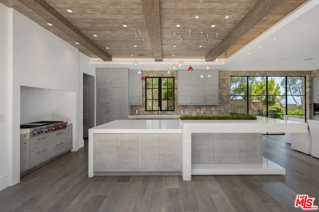 a large room with kitchen island a large counter space a sink and a large window