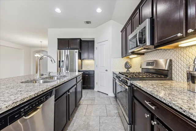 a kitchen with stainless steel appliances granite countertop a sink stove and refrigerator
