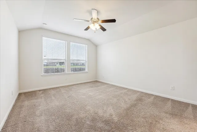 an empty room with ceiling fan and windows