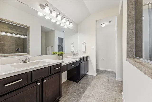 a spacious bathroom with a granite countertop sink a large mirror and a shower