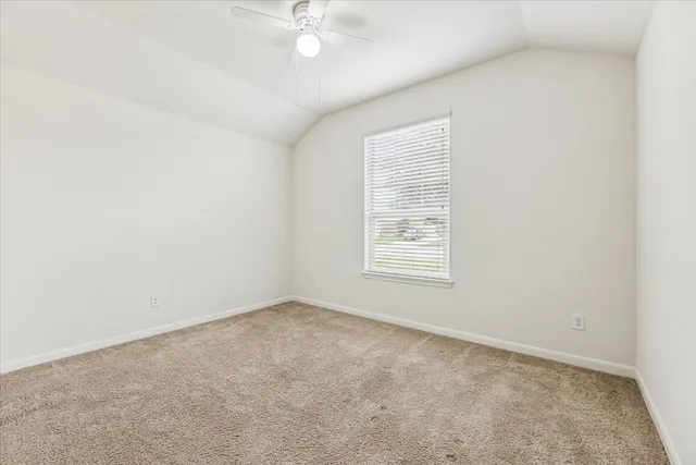 an empty room with a chandelier fan and windows