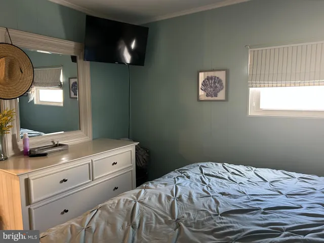 a bedroom with a bed and a flat tv screen on dresser