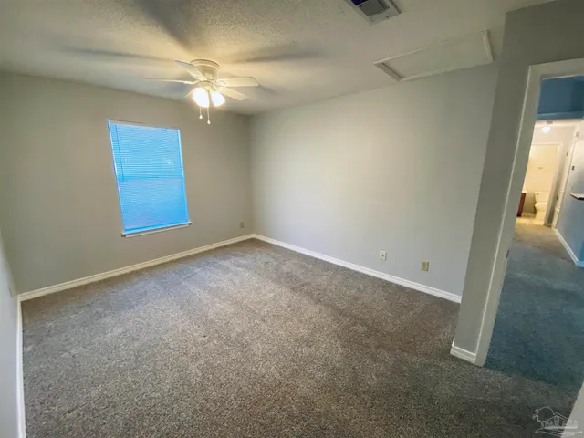 an empty room with a chandelier fan and windows