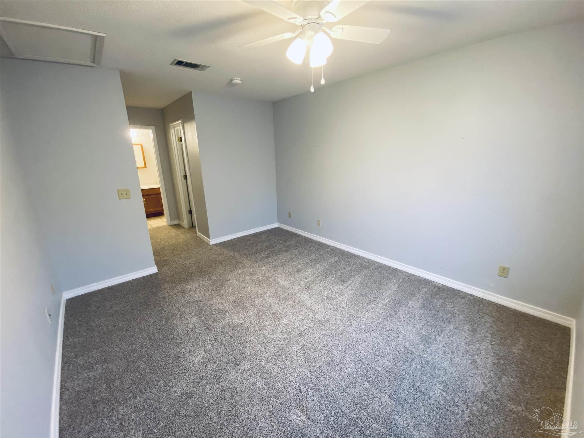1000 Sable Drive, Unit B Pensacola, FL 32514 - Photo 8 of 10 an empty room with a chandelier fan and windows