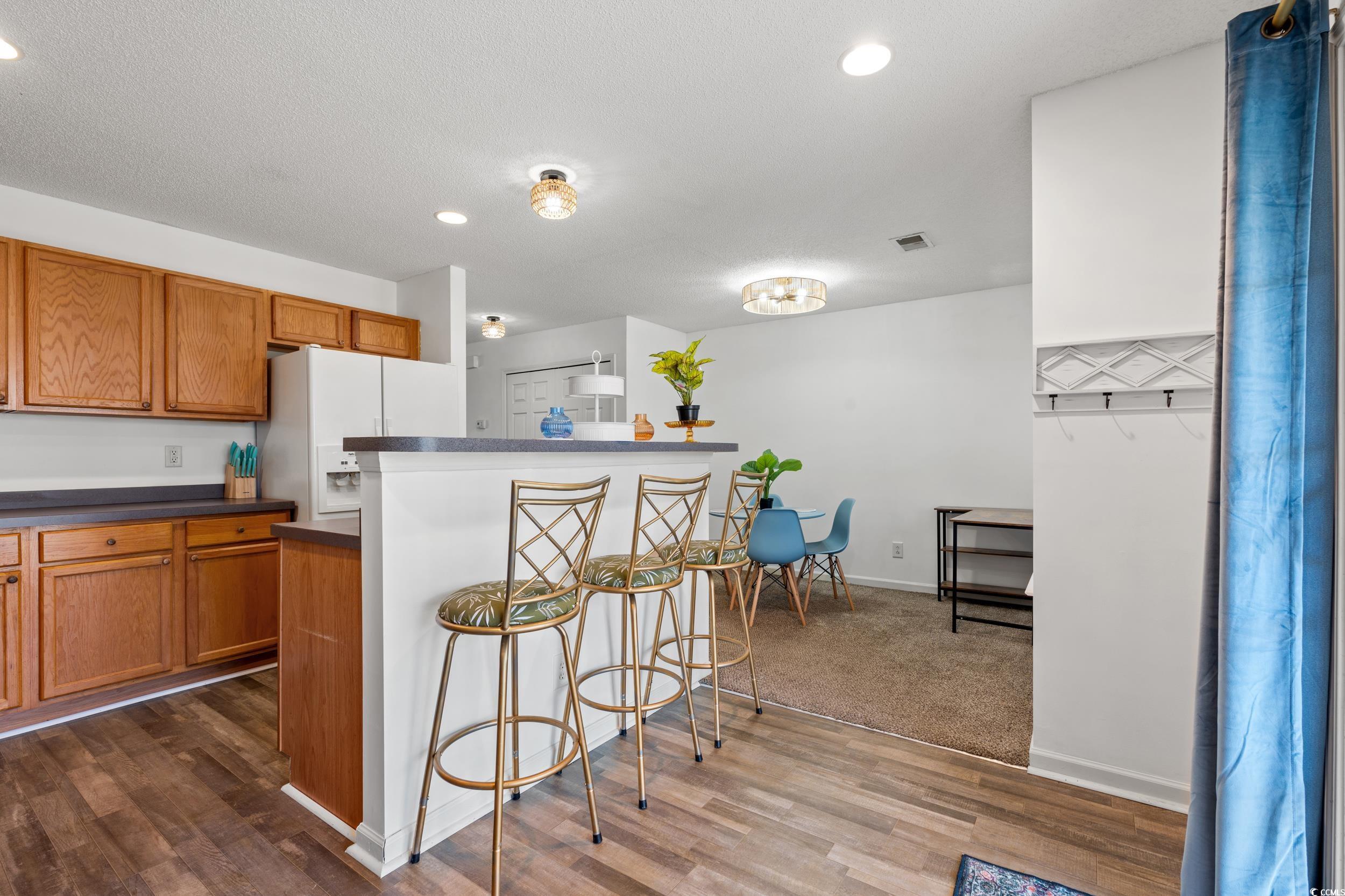 270 Seabert Road, Unit 270 Myrtle Beach, SC 29579 - Photo 8 of 31 Kitchen featuring white appliances, dark countertops, wood finished floors, a textured ceiling, and brown cabinetry