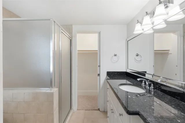 a bathroom with a granite countertop double vanity sink and mirror