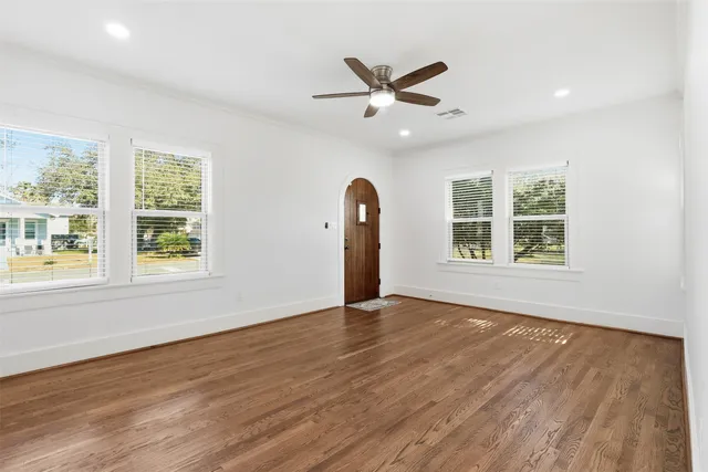 a view of an empty room with a window and wooden floor