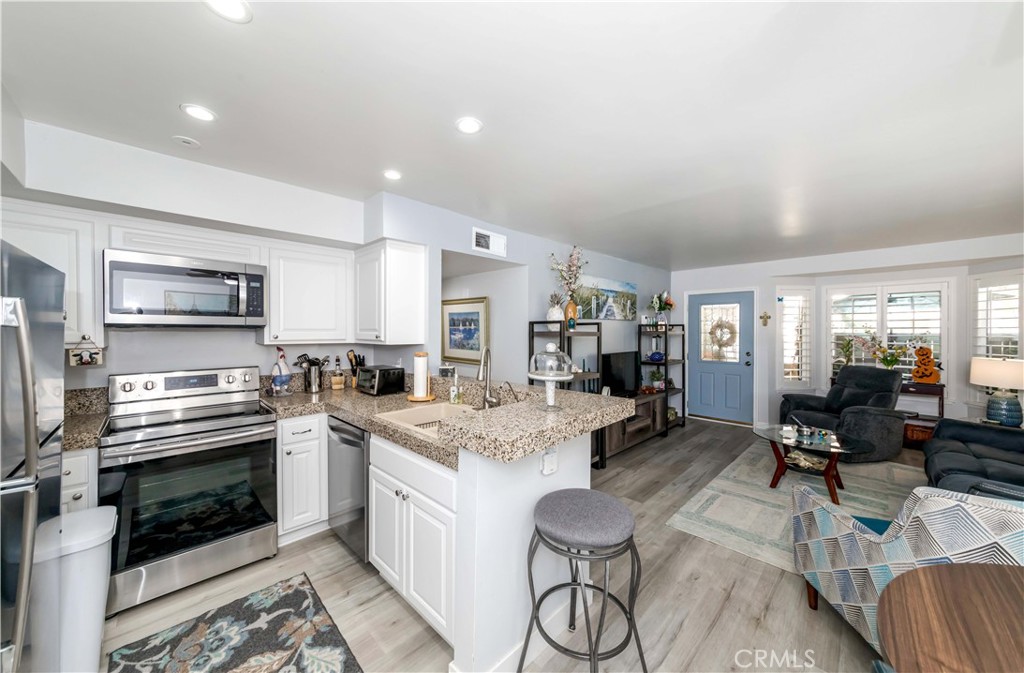 12671 Briarglen Loop, Unit G Stanton, CA 90680 - Photo 12 of 24 a kitchen with stainless steel appliances kitchen island granite countertop a stove and white cabinets