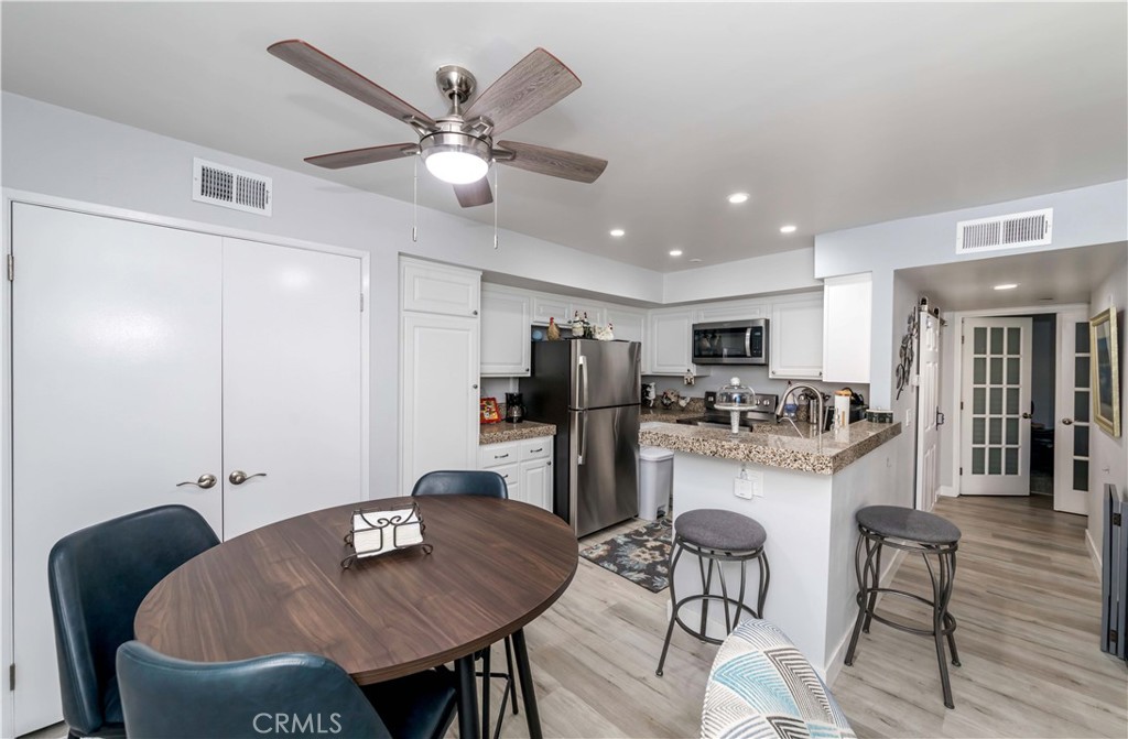 12671 Briarglen Loop, Unit G Stanton, CA 90680 - Photo 13 of 24 a kitchen with stainless steel appliances kitchen island granite countertop a dining table chairs and a refrigerator