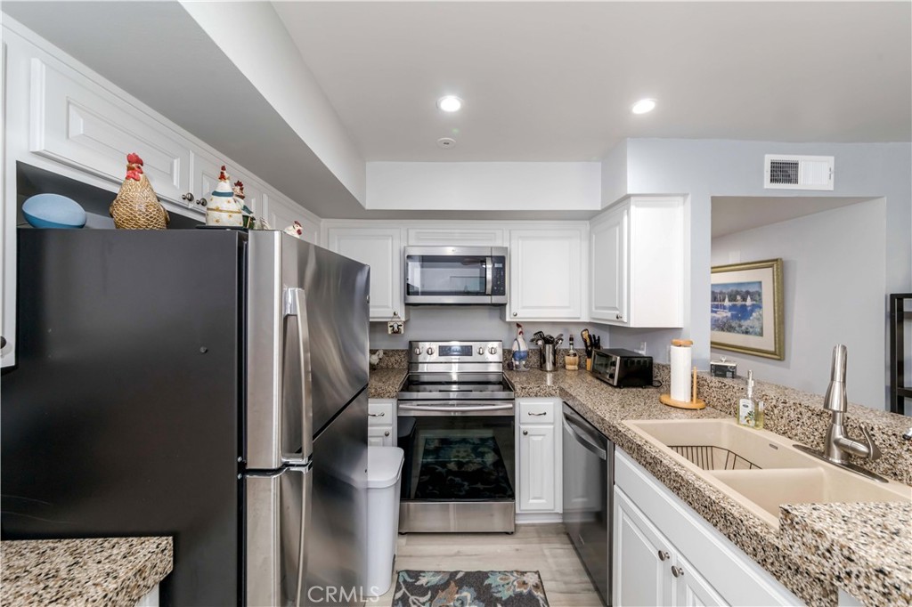 12671 Briarglen Loop, Unit G Stanton, CA 90680 - Photo 7 of 24 a kitchen with stainless steel appliances granite countertop a refrigerator a stove and a sink