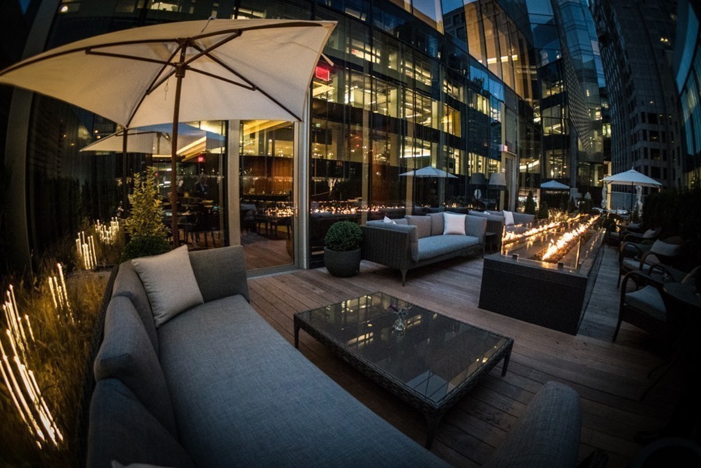 1 Franklin Street, Unit PH 2D Boston, MA 02110 - Photo 17 of 26 a view of a patio with couches table and chairs under an umbrella