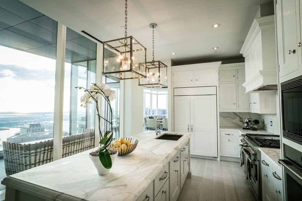 1 Franklin Street, Unit PH 2D Boston, MA 02110 - Photo 4 of 26 a kitchen with stainless steel appliances kitchen island granite countertop a table chairs in it and wooden floors