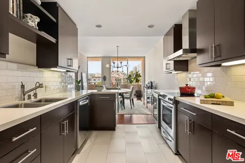 a kitchen with stainless steel appliances a sink dishwasher a stove top oven a refrigerator with wooden cabinets and floor