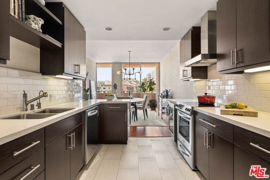 1333 South Beverly Glen Boulevard, Unit 703 Los Angeles, CA 90024 - Photo 8 of 18 a kitchen with stainless steel appliances a sink dishwasher a stove top oven a refrigerator with wooden cabinets and floor