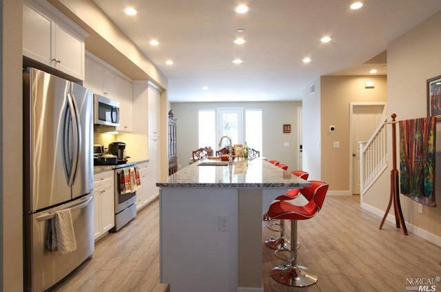 a kitchen with stainless steel appliances granite countertop a refrigerator and a stove top oven with wooden floor