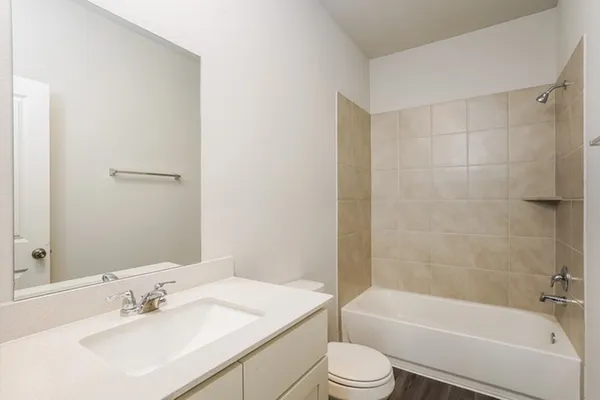 a bathroom with a bathtub shower sink vanity mirror and toilet