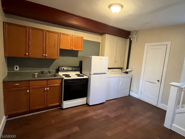 a kitchen with granite countertop a refrigerator a sink dishwasher stove and white cabinets