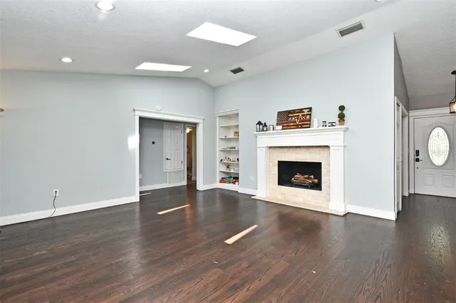 a view of a livingroom with wooden floor and a kitchen