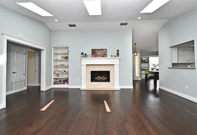 a view of an empty room with wooden floor fireplace and a window