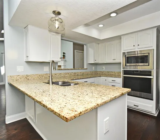 a kitchen with granite countertop white cabinets stainless steel appliances and sink