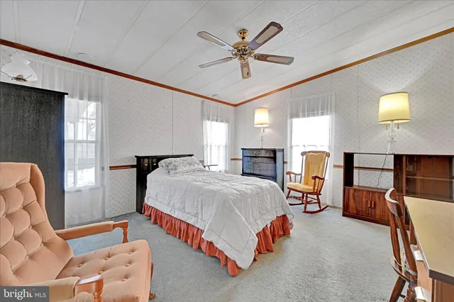 a bedroom with a bed dresser and a large window