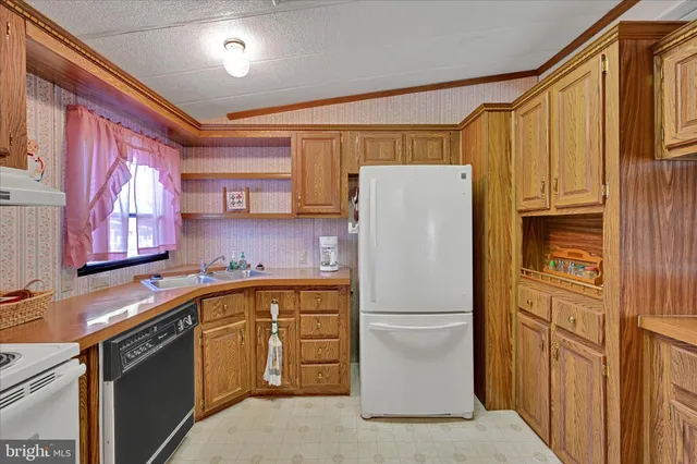 a white refrigerator freezer sitting in a kitchen with stainless steel appliances granite countertop a refrigerator and a sink