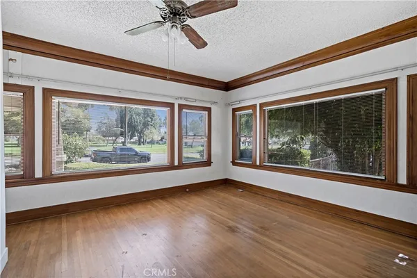 a view of empty room with wooden floor and fan