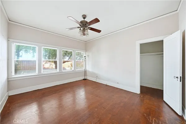 a view of an empty room with a window and wooden floor