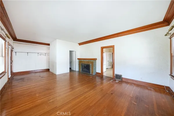 an empty room with wooden floor fireplace and windows