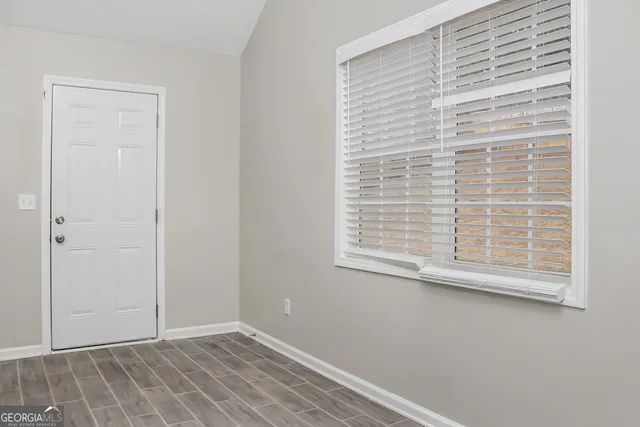 an empty room with wooden floor fireplace and windows