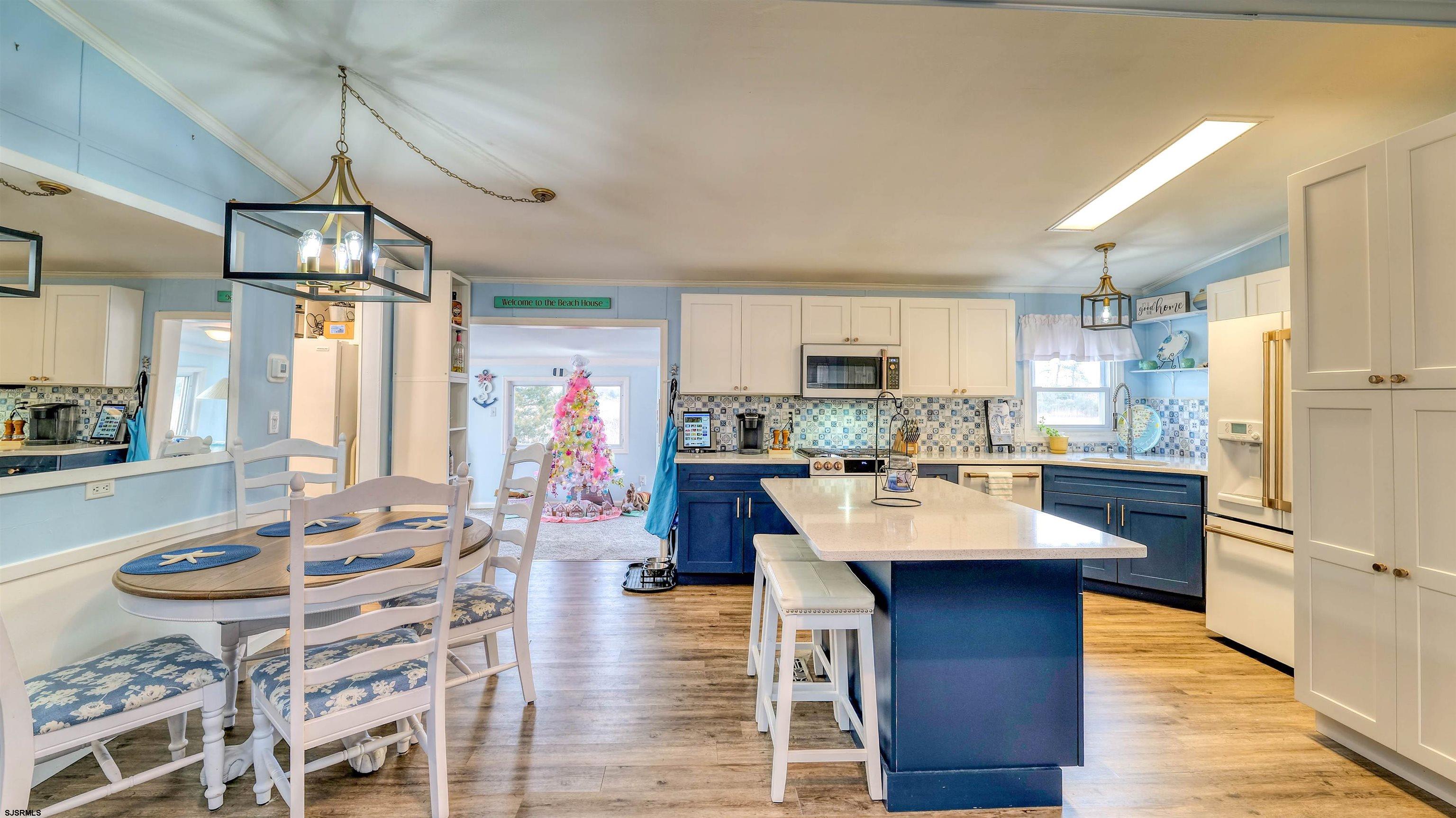 33 Defeo Lane Somers Point, NJ 08244 - Photo 8 of 29 a kitchen with stainless steel appliances kitchen island granite countertop a refrigerator a stove top oven and a dining table with wooden floor