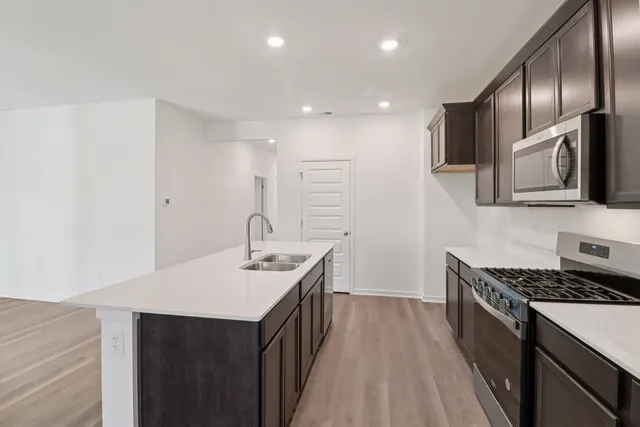 a kitchen with stainless steel appliances granite countertop a sink a stove and a wooden floors