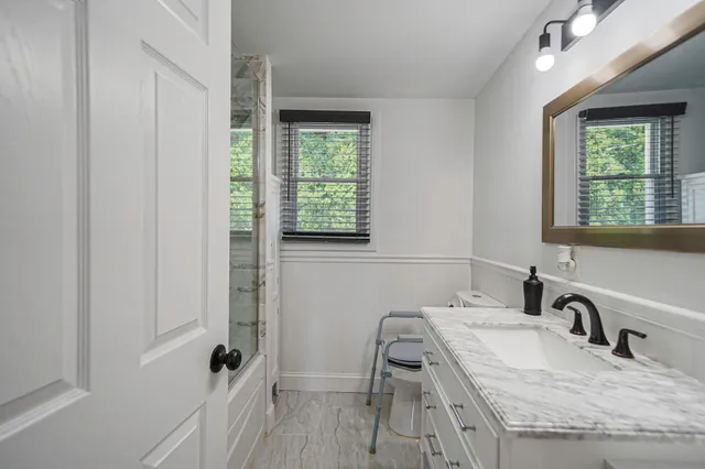 a bathroom with a granite countertop sink a toilet and a window