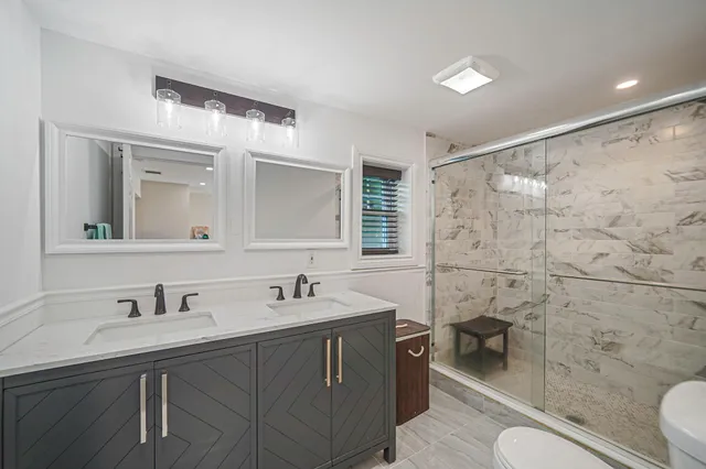 a bathroom with a sink toilet a mirror and shower